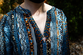 Photo depicts model with patterned shirt wearing the angel wing heart pendant on a chain around her neck. Silver angel jewelry, angel necklace for ash, silver necklace for ash, necklace for cremation ash